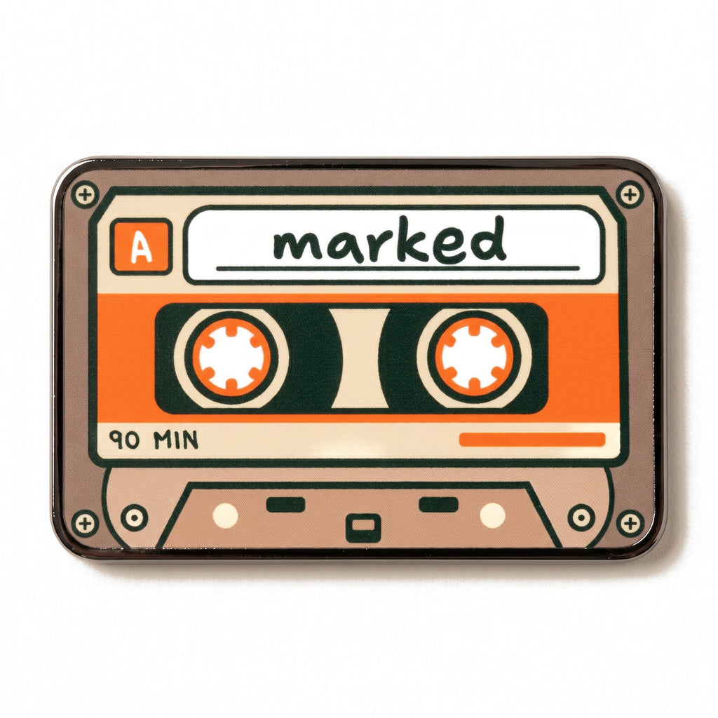 The Soundtrack golf ball marker photographed flat from above, showing the full cassette design and the black nickel edge.