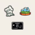 The Group Chat ball marker set photographed flat from above on a cream background: a white chef hat, a fairway scene reading TOUCH GRASS, a black charge card, and the chrome Monogram Signature marker.