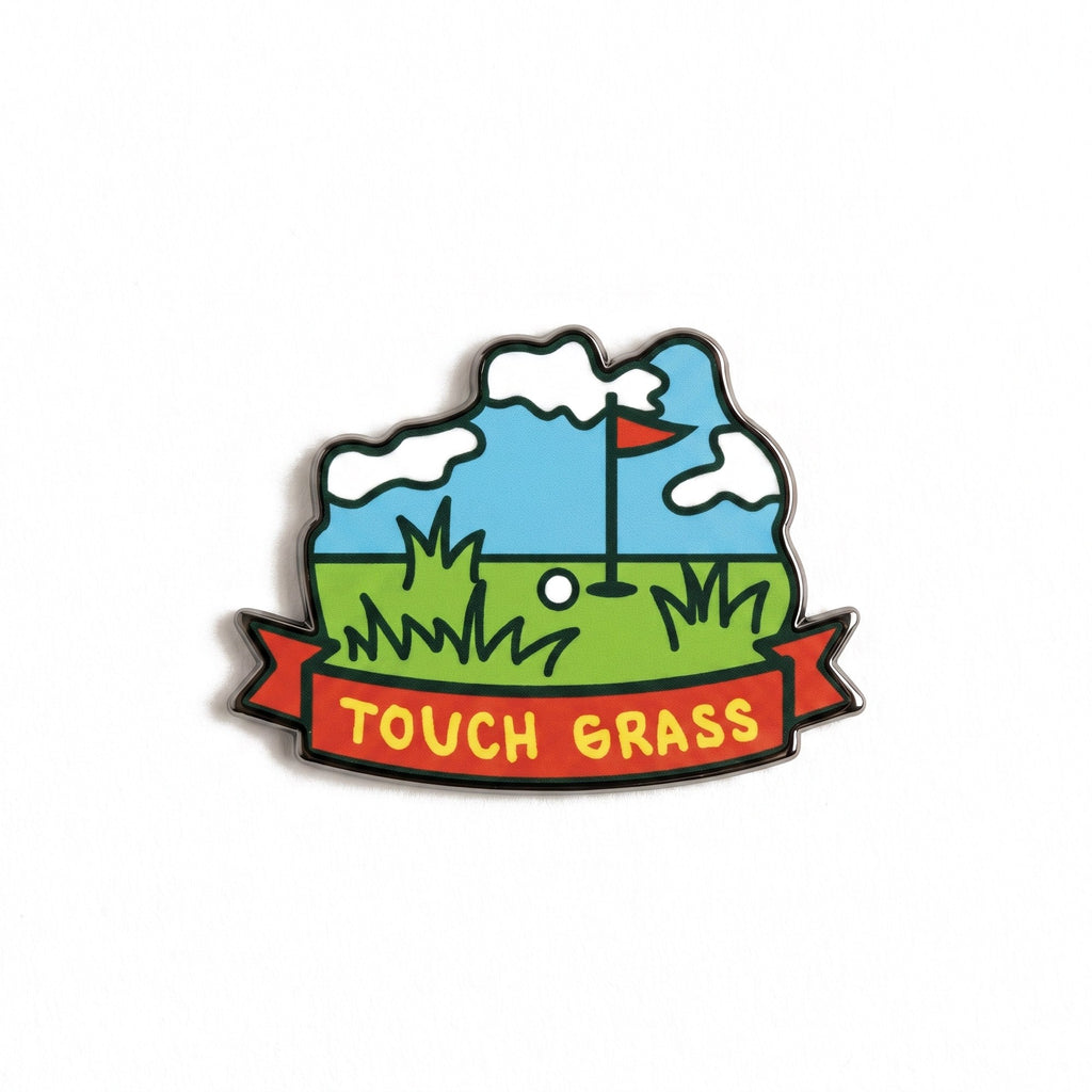The Touch Grass golf ball marker photographed flat from above, showing the full scene and the black nickel edge.